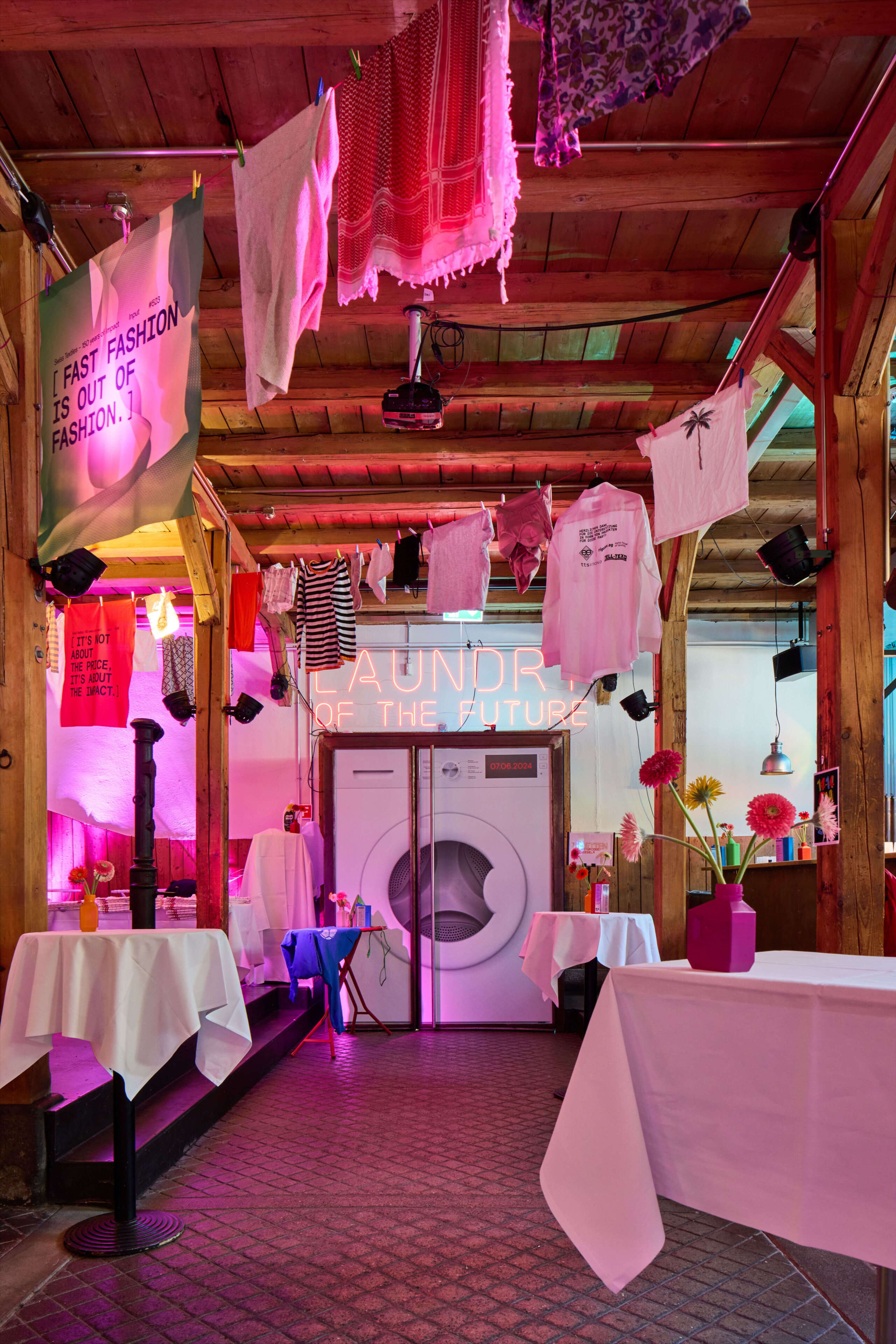 evenjo_swisstextiles_jubilaeum.jpg Inszenierung „Laundry of the Future“ mit Neon-Schriftzug und aufgehängten Textilien – visionärer Blick auf die Textilbranche von morgen. Zukunftsdesign, Textilbranche, Installationskunst, Innovationsshow, Waschmaschinen-Event, markenerlebnis, Brand Experience, Riithalle Zürich, Dekoration, jubiläumsfeier, mitarbeiteranlass, live kommunikation