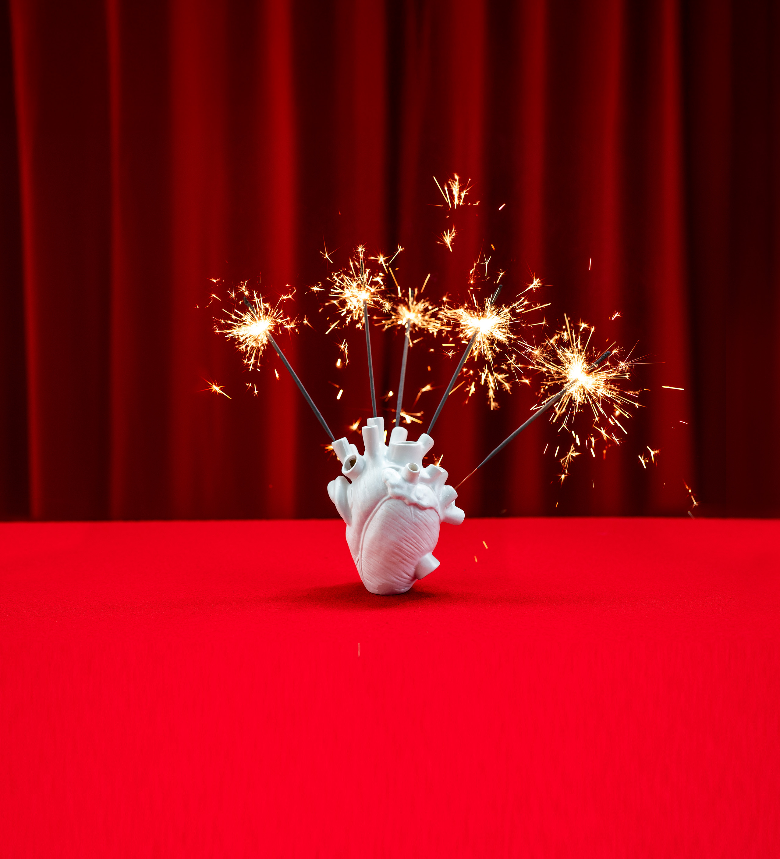 Herzmodell_mit_Wunderkerzen.jpg Weisses Herzmodell mit Wunderkerzen vor rotem Vorhang. Eventdesign, kreative Deko, visuelles Storytelling für Veranstaltungen, Markenerlebnis, Brand Experience, Eventplanung, Publicevent, Eventagentur Bern, Technik, Beleuchtung, Live Kommunikation