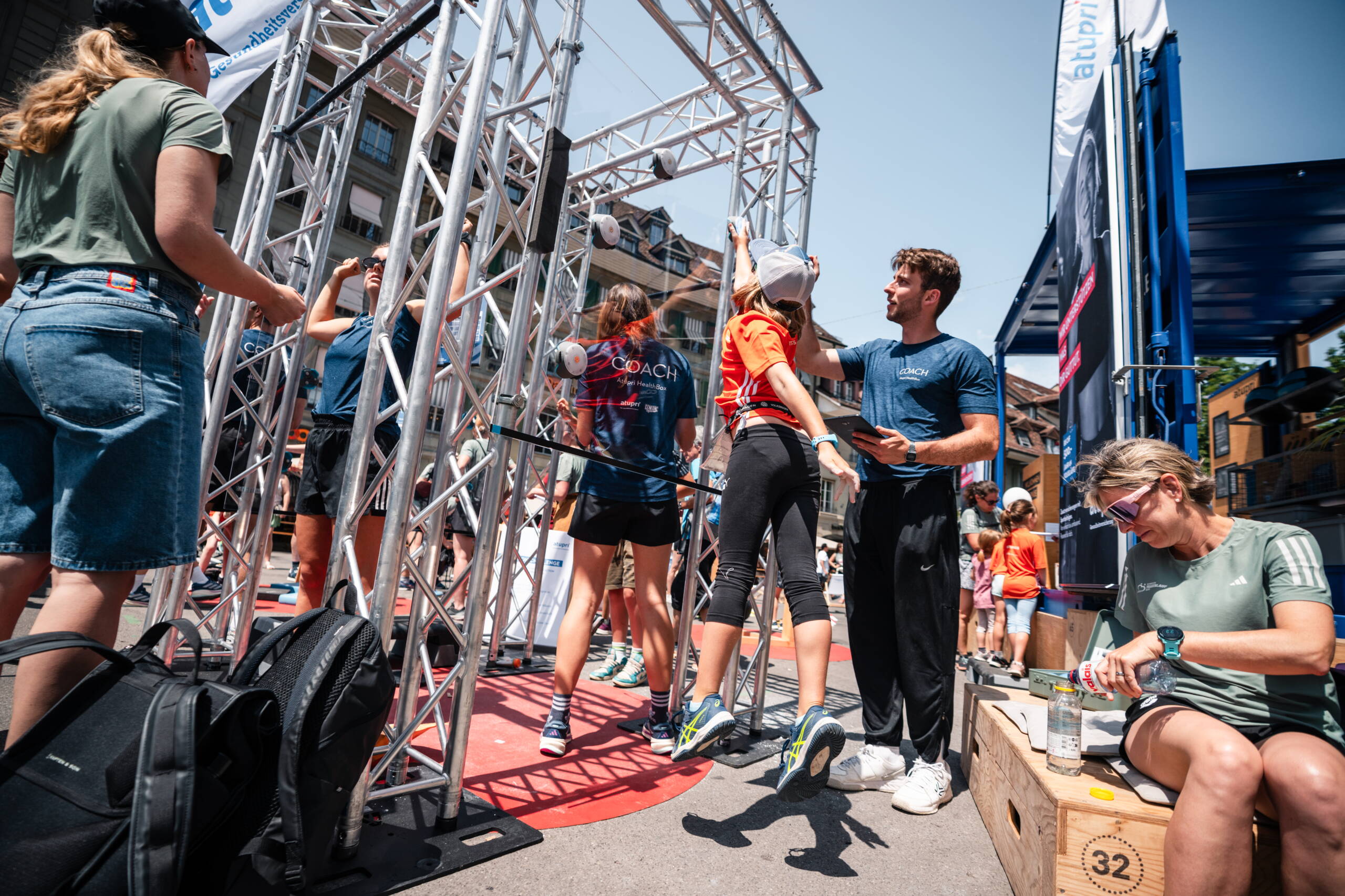 healthbox-am-frauenlauf.jpg Mädchen wird bei Fitnessparcours der Atupri Healthbox angeleitet, während Coaches unterstützen und beobachten. Kinderfitness, Coach-Betreuung, Gesundheitsförderung, Bewegungsförderung, Parcours, live kommunikation, Corporate-Event, Eventagentur bern, eventplanung, firmenevents, teamevents bern, jubiläumsfeier, networking anlass, mitarbeiter:innenanlass, Technik, Public Events, Sport und Entertainment Events, markenerlebnis, Brand Experience
